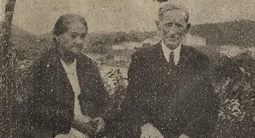 Foto histórica do casal pioneiro Willis e Vicência Banks, sentados em frente a uma paisagem de rio e morros, no Vale do Ribeira.